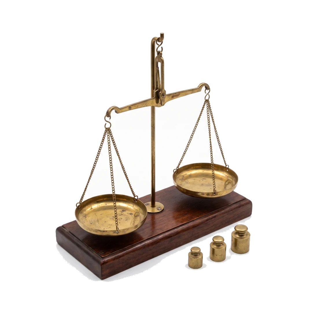 An old brass beam balance with two shallow pans on a wooden base, worn with age.