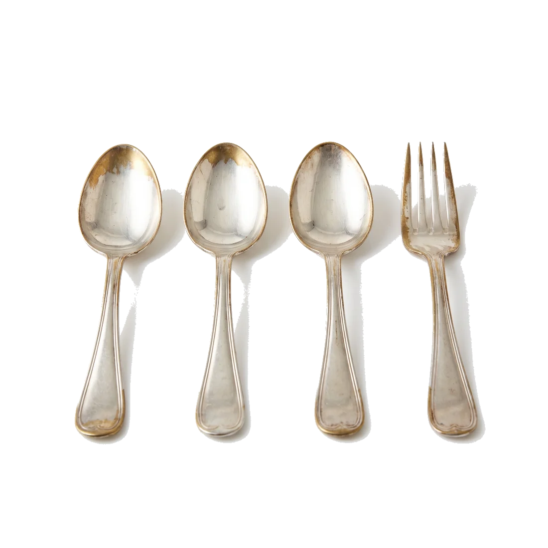 Plated spoons and a fork with the plating worn through to yellowish base metal at the tips.