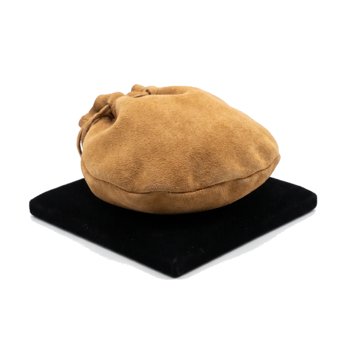 A closed, full suede drawstring pouch resting on a black velvet counter pad.