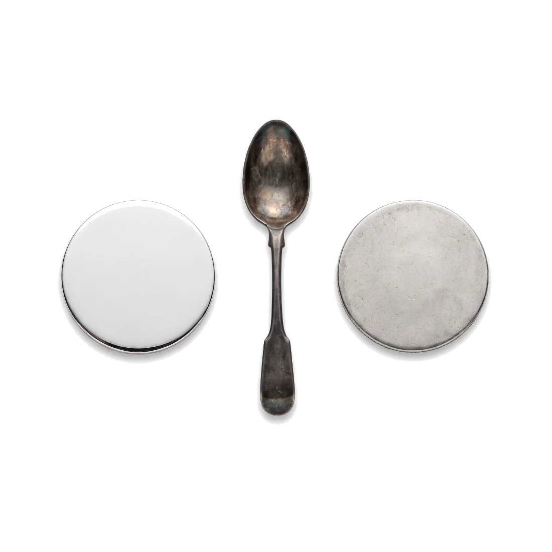 A plain bright silver disc, a tarnished teaspoon and a worn smooth silver coin in a row.